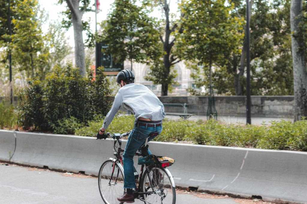 Man in jeans biking to work on a city street.
